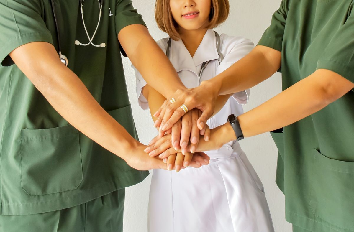 Doctors and nurses in a medical team stacking hands. Surgeon medical people handshaking. Medical personnel in uniform working together in clinic. greeting power of tag team