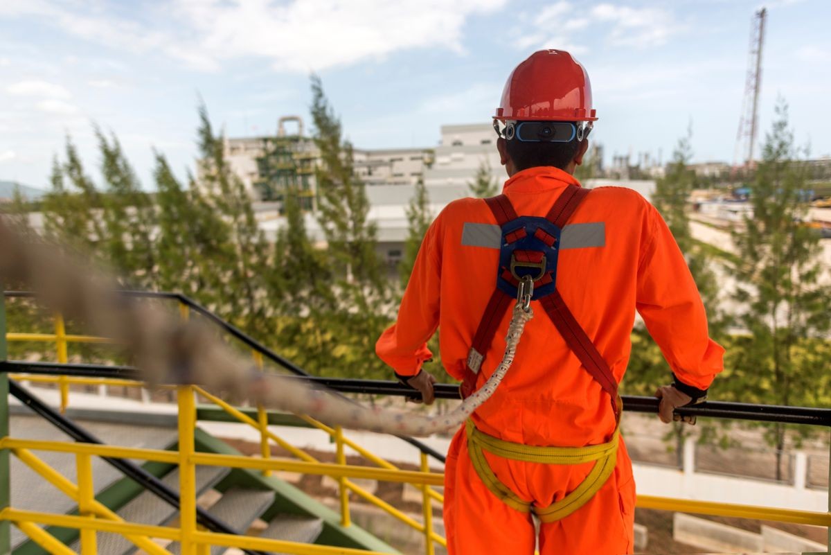 Worker in safety harness on high construction site . Concept for occupational health safety in construction.